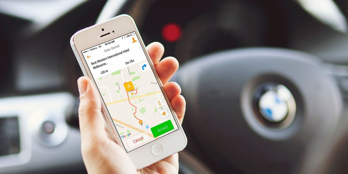 A person holding a smartphone showing a ride-hailing app with a map and directions inside a car